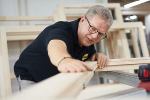 Firmenportrait: Mann am Holz beim Arbeiten